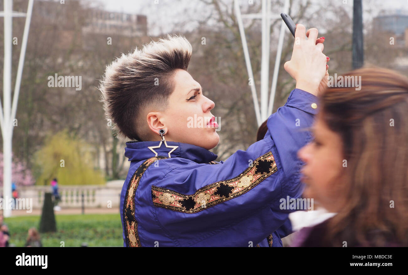Eine junge unverwechselbare Frau ein Foto auf Ihrem Smartphone in den Bereich vor dem Buckingham Palace, London Stockfoto
