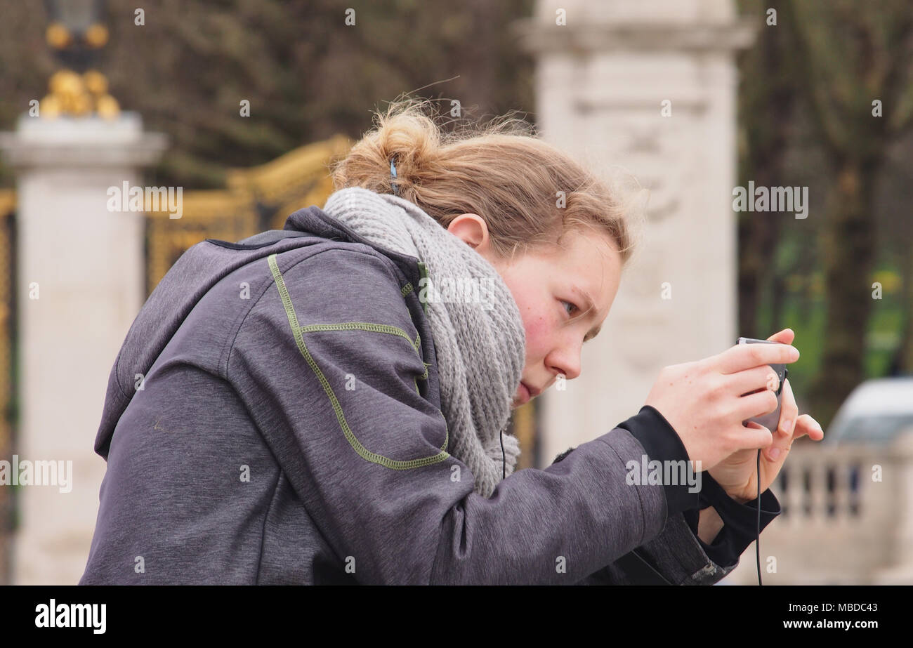 Eine junge Frau, die das Komponieren ein Foto mit Ihrem Smartphone in den Bereich vor dem Buckingham Palace, London Stockfoto