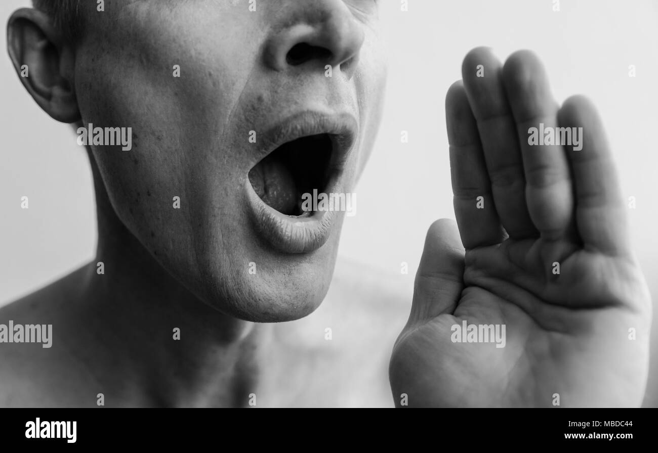 Mund und Hand öffnen. Der untere Teil des Gesichts des Mannes Nahaufnahme. Schwarz-weiß Bilder. Stockfoto