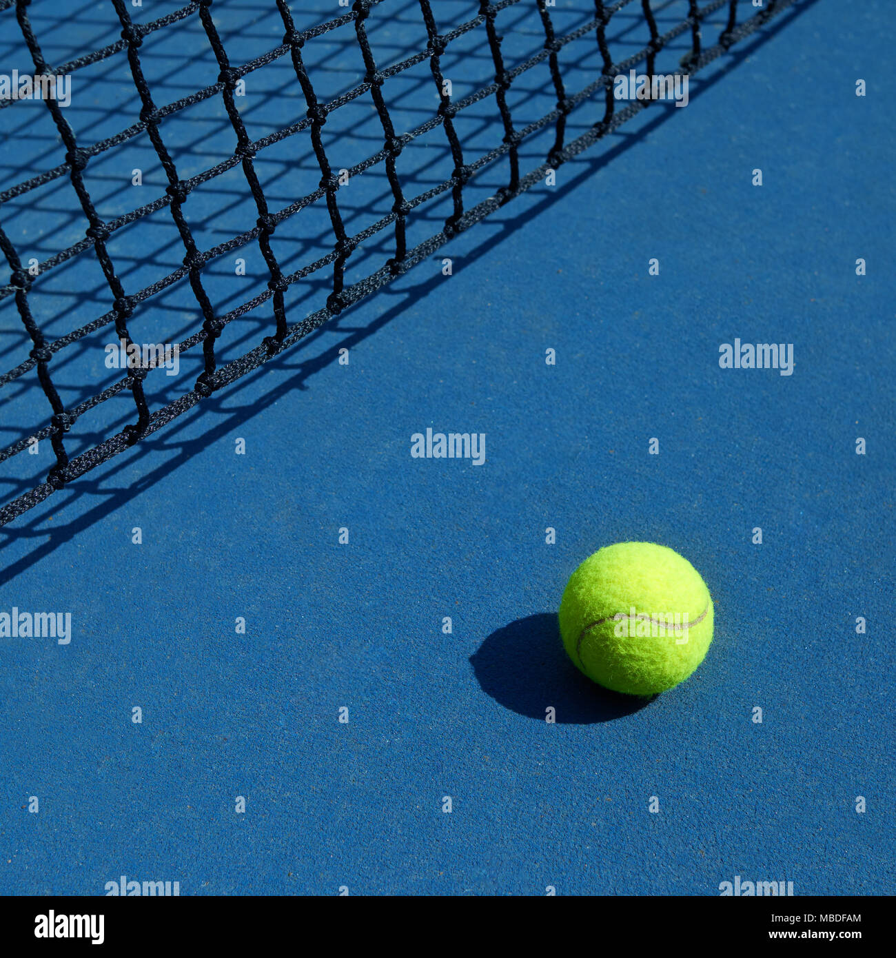 Gelbe Tennisball ist die Verlegung in der Nähe von Schwarzen geöffnet Tennisplatz net. Kontrast Image des Sports Equipment mit satureted Farben und Schatten. Konzept der Tennis Outfit photografing. Stockfoto