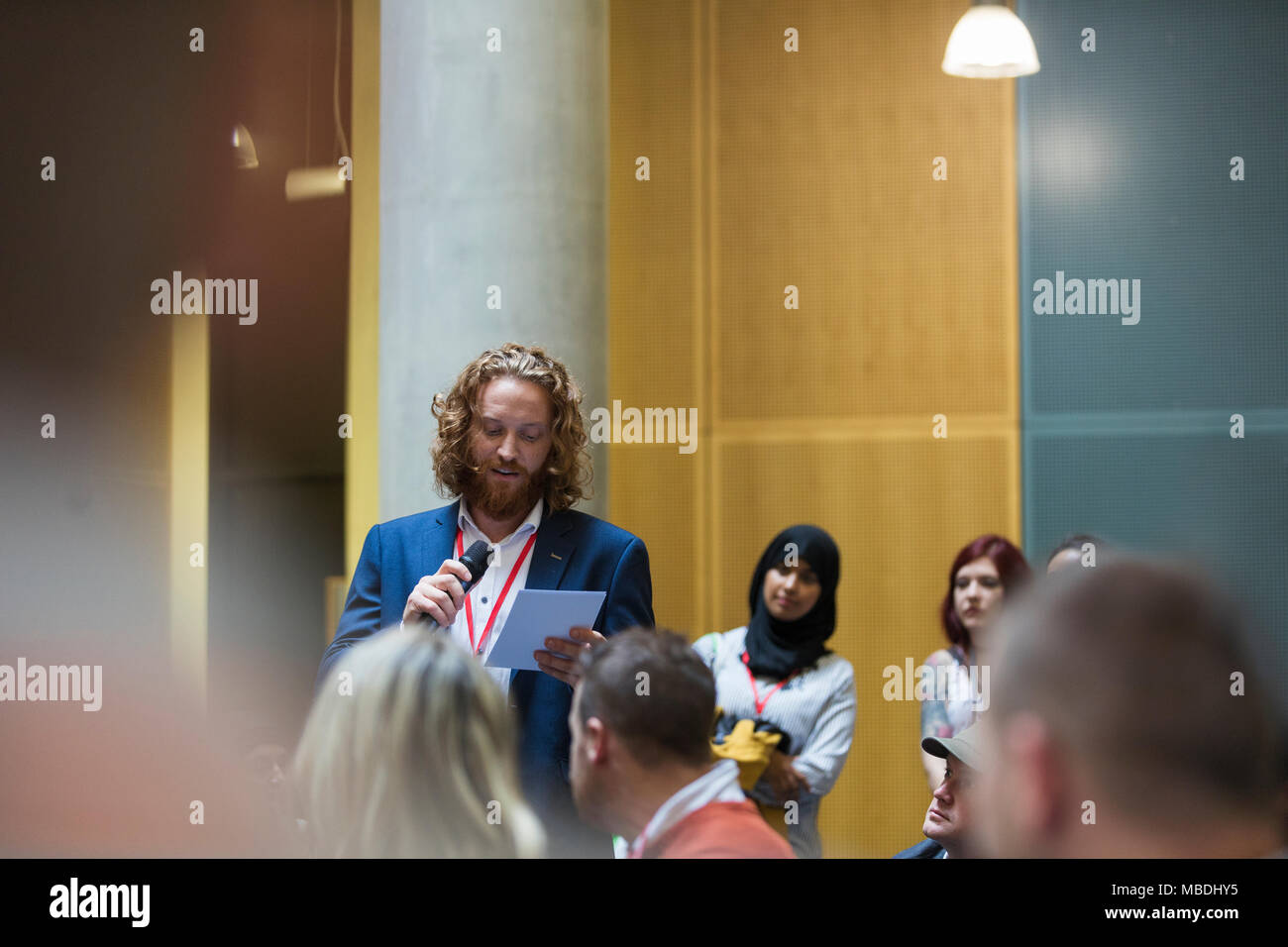 Geschäftsmann mit Mikrofon und Notizen Gespräch mit Publikum Stockfoto Geschäftsmann mit Mikrofon und Notizen Gespräch mit Publikum Stockfoto
