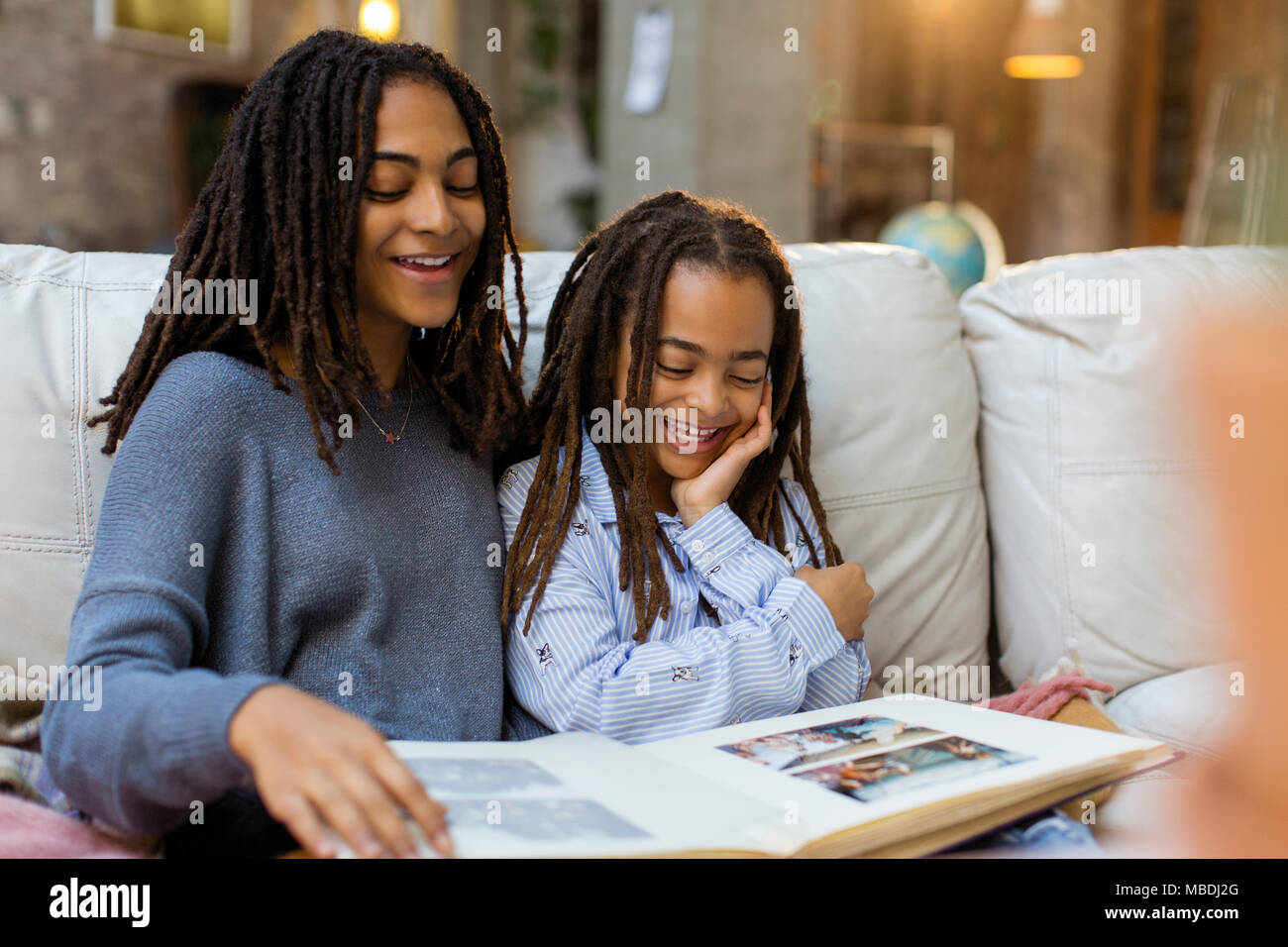 Lächelnde Schwestern an Foto Album suchen Stockfoto