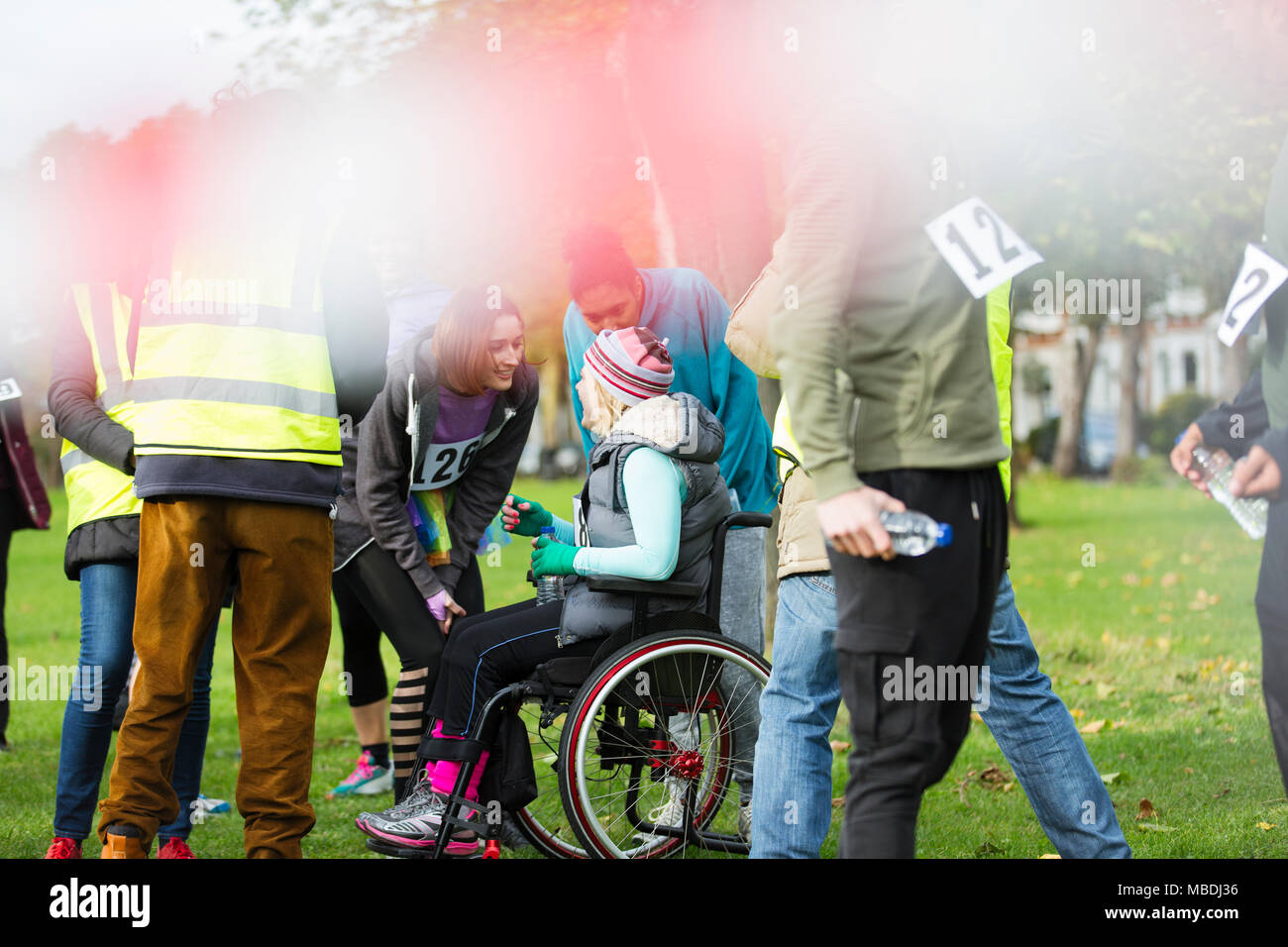 Frau im Rollstuhl Gespräch mit Freunden an der Nächstenliebe Rennen in Park Stockfoto