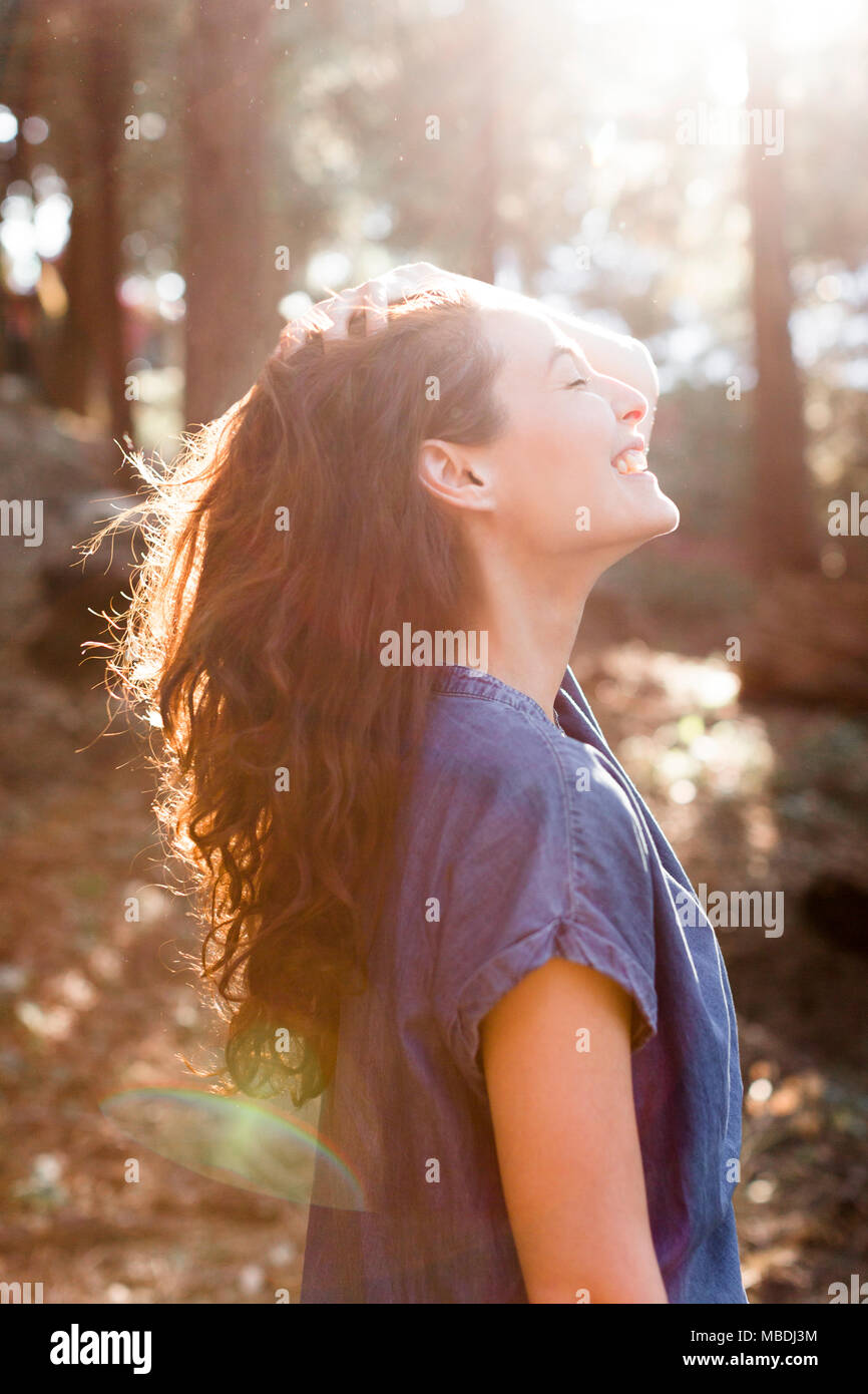 Lächelnd, unbekümmerte Frau in Sunny woods Stockfoto