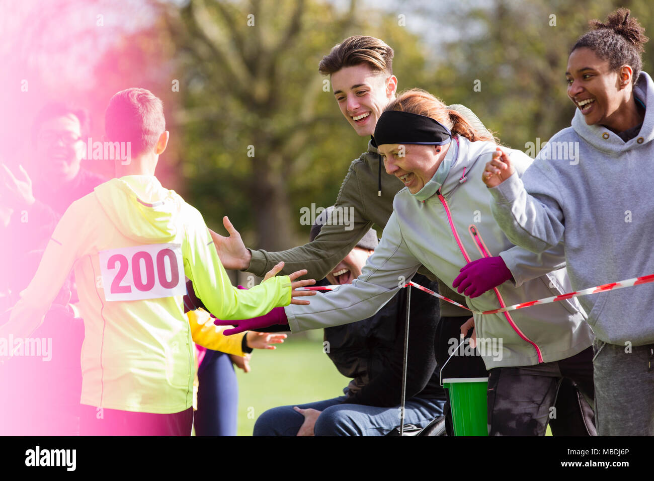 Zuschauer, high-fiving Runner an der Nächstenliebe laufen im Park Stockfoto