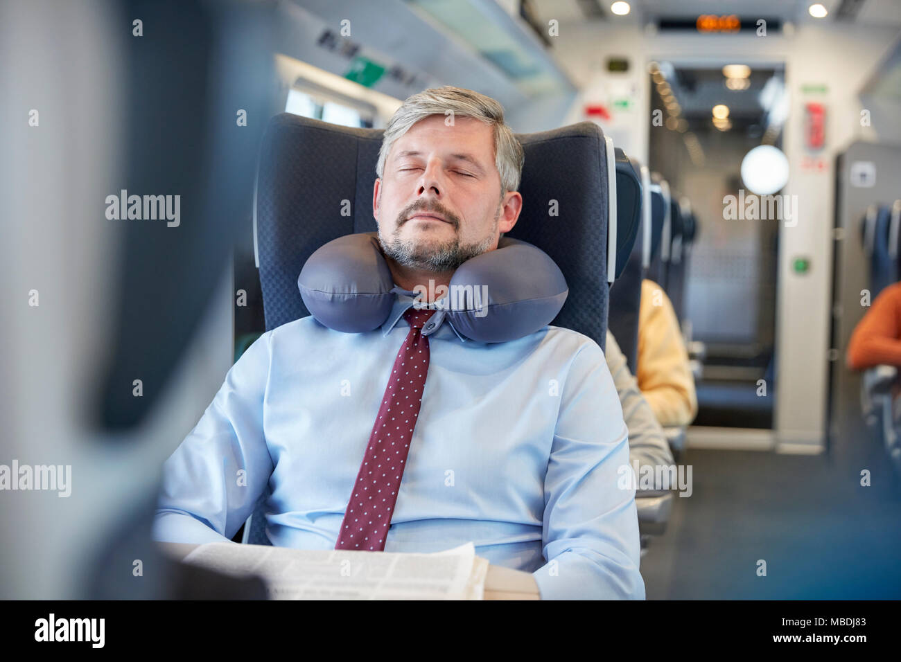 Müde Geschäftsmann mit Nackenkissen schlafen auf Personenzug Stockfoto