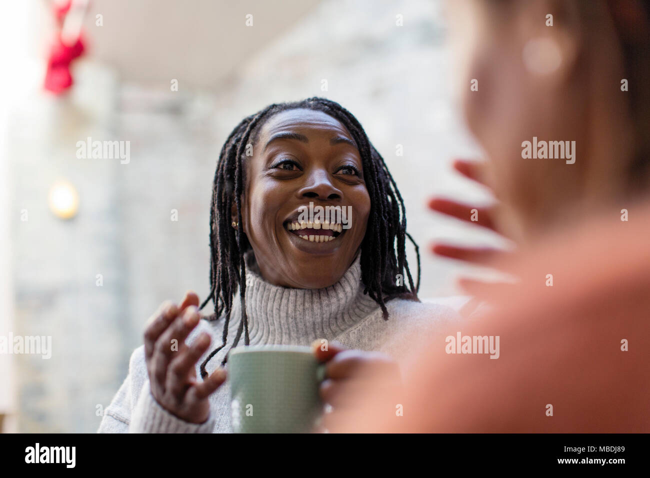Begeisterte Frau trinkt Kaffee, im Gespräch mit Freund Stockfoto
