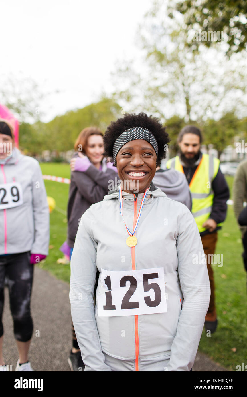 Porträt Lächeln, zuversichtlich Läuferin das Tragen einer Medaille bei spendenlauf in Park Stockfoto