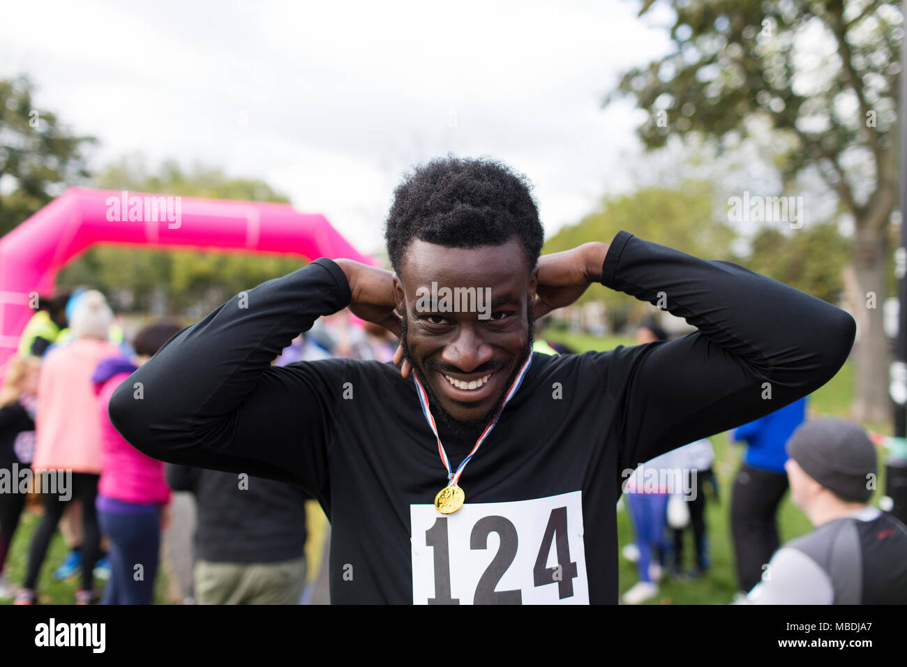 Porträt Lächeln, selbstbewusste männliche Läufer tragen Medaille an spendenlauf in Park Stockfoto
