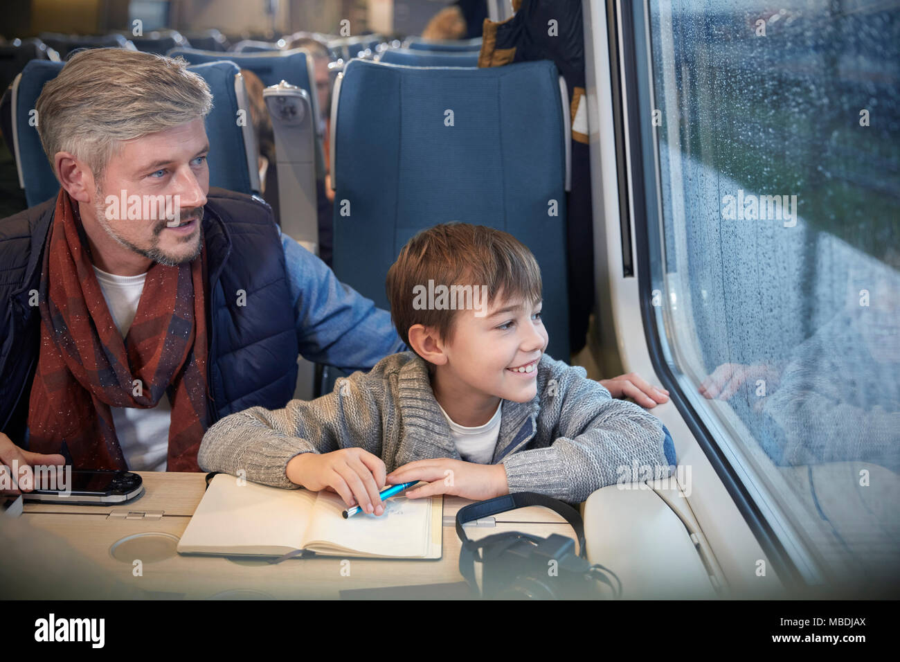 Vater und Sohn Blick aus Fenster auf Personenzug Stockfoto