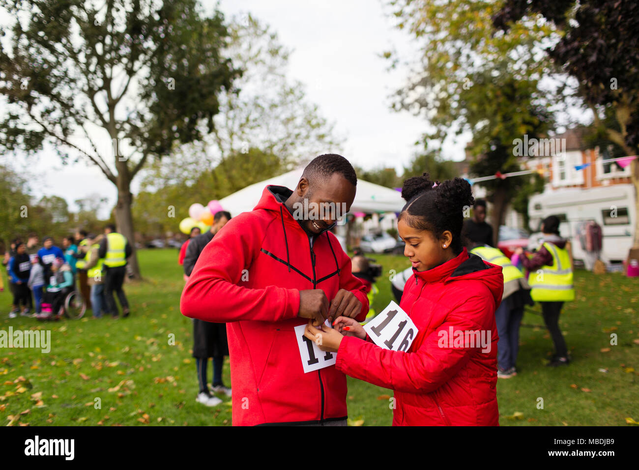 Tochter pinning Marathon bib auf Vater Runner an der Nächstenliebe laufen im Park Stockfoto