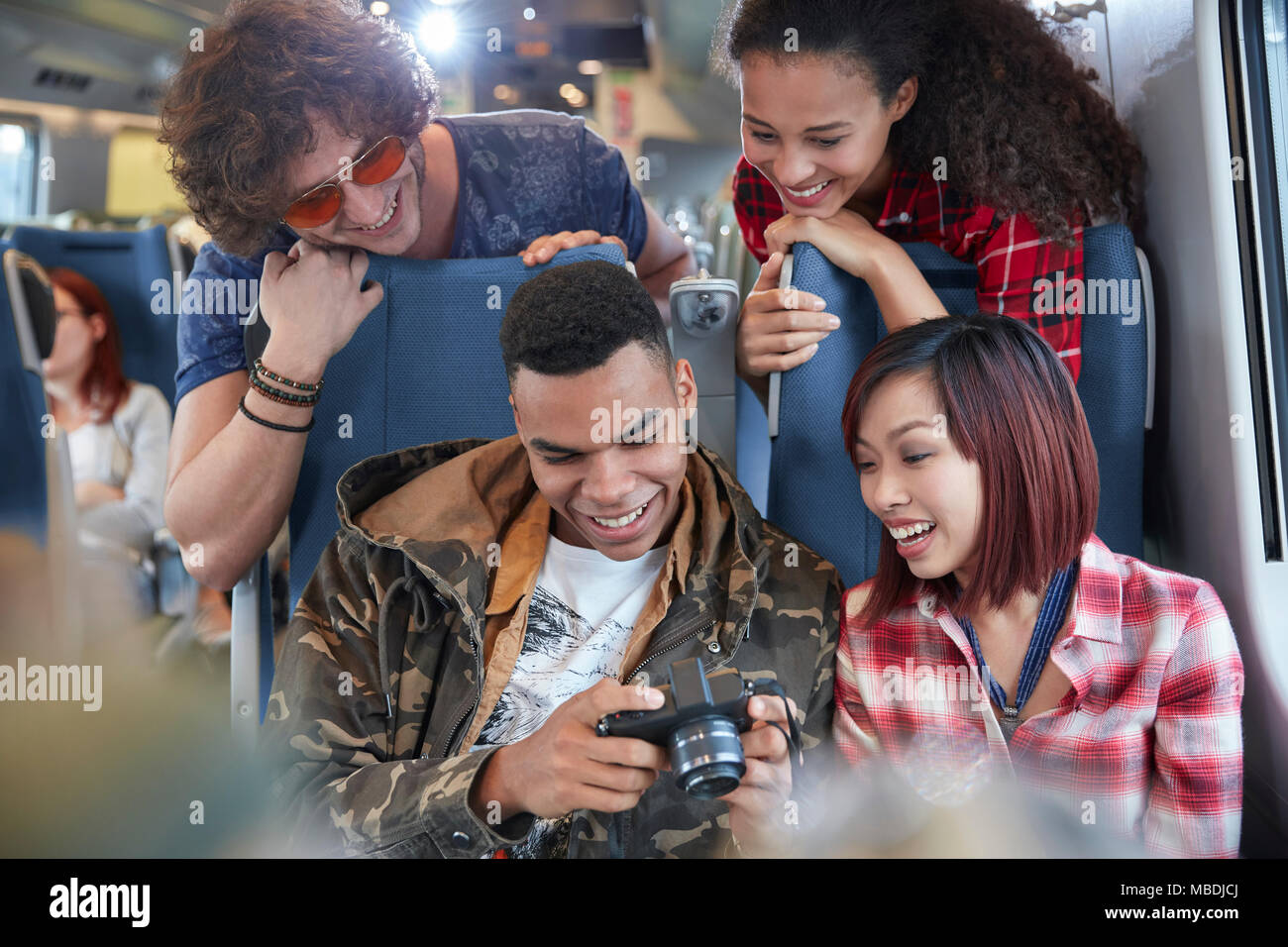 Junge Freunde das Betrachten von Fotos auf Digitalkamera auf Personenzug Stockfoto