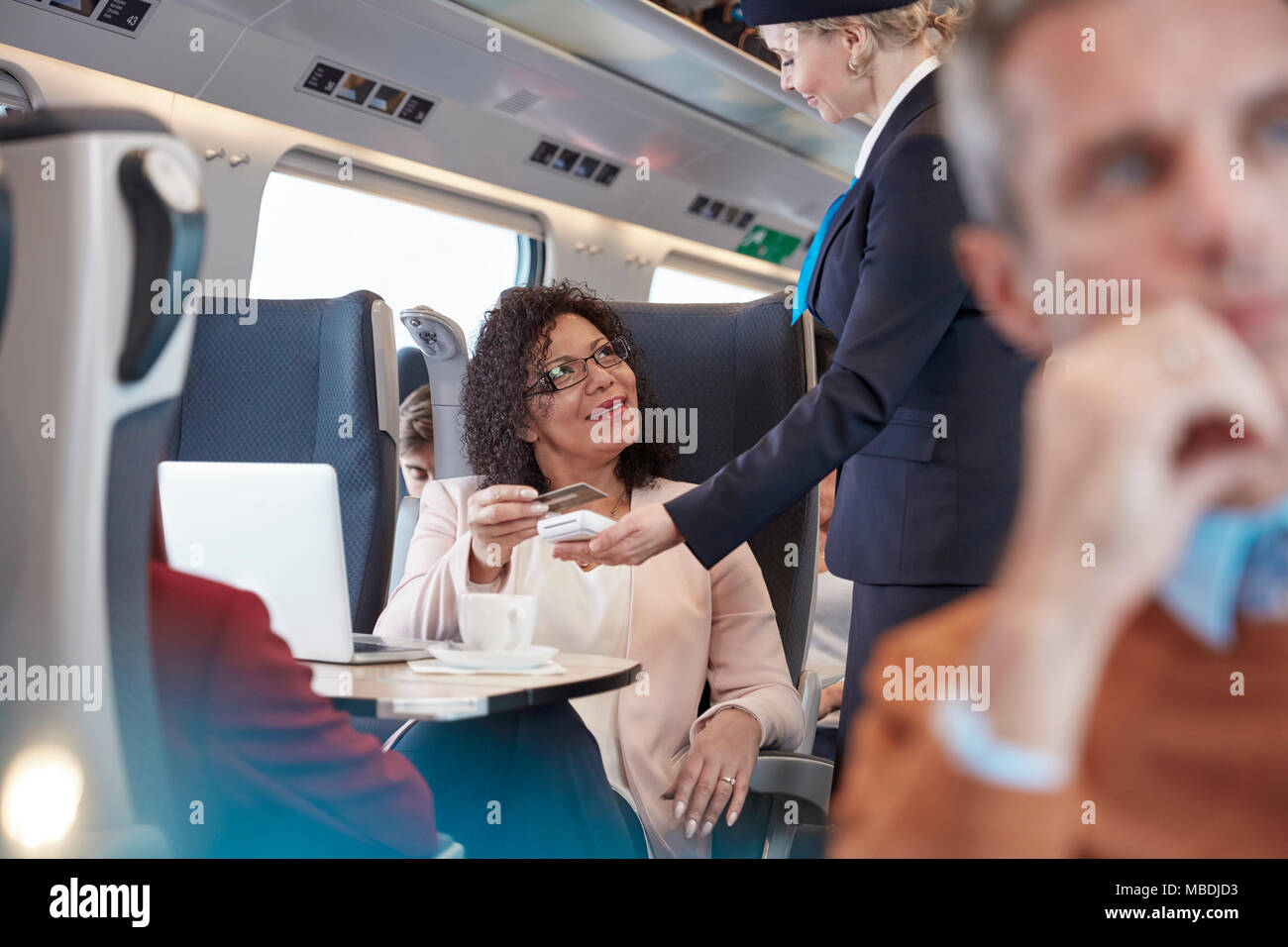 Frau mit Kreditkarte über das kontaktlose Bezahlen, wobei Attendant auf Personenzug Stockfoto