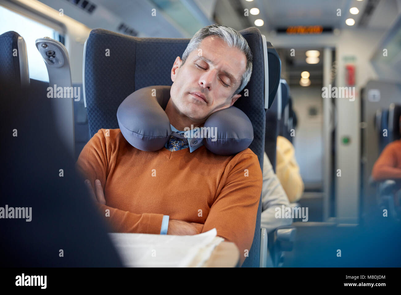 Müde Geschäftsmann mit Nackenkissen schlafen auf Personenzug Stockfoto