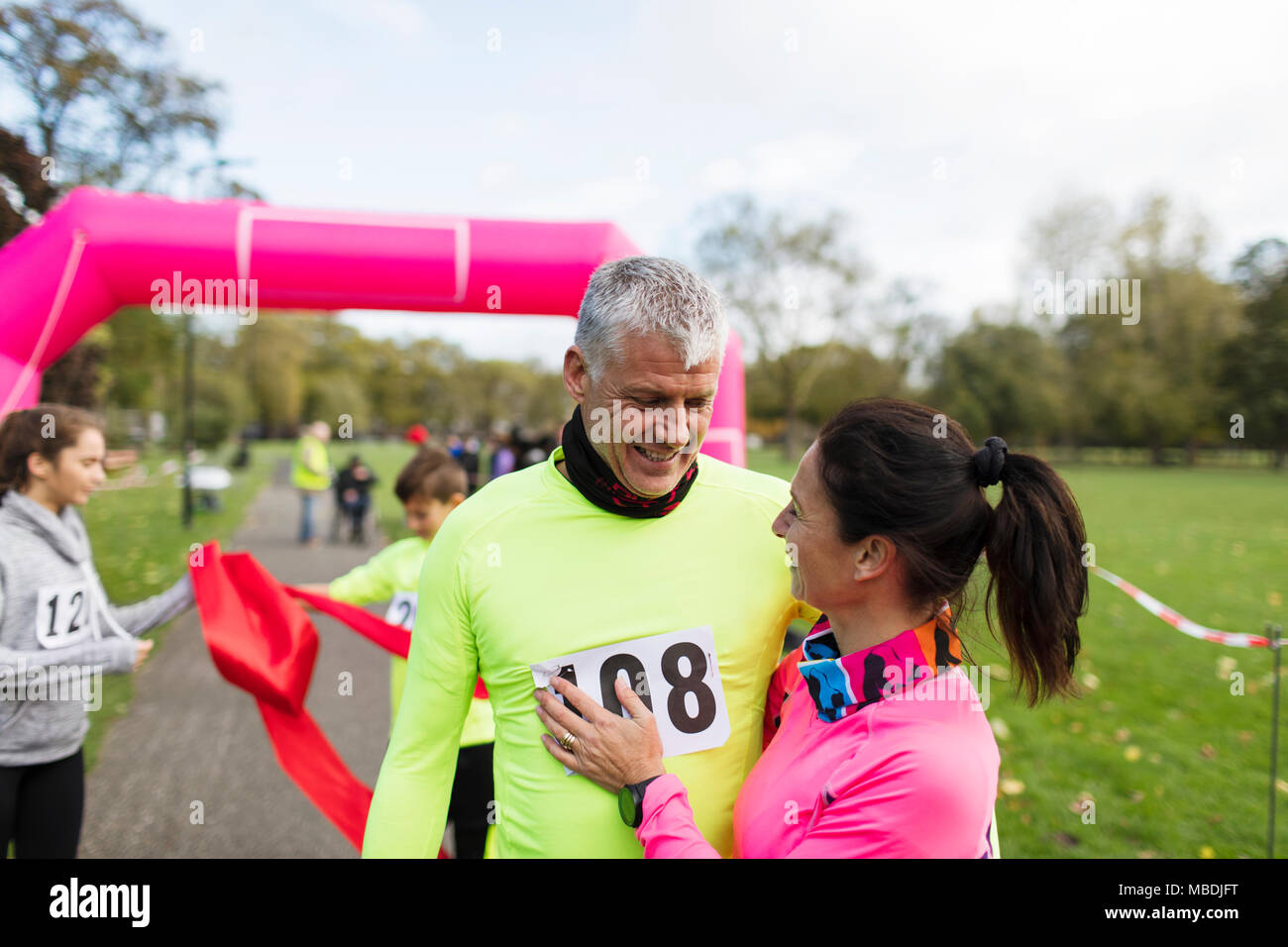 Glückliches Paar Läufer umarmen an der Ziellinie an der Nächstenliebe laufen im Park Stockfoto