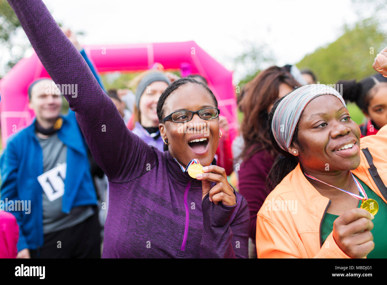 Begeisterte Läuferinnen mit Medaillen jubeln, Feiern im Charity Run Stockfoto