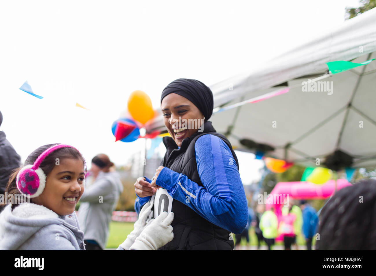 Lächelnd Tochter pinning Marathon bib auf Mutter an der Nächstenliebe ausführen Stockfoto