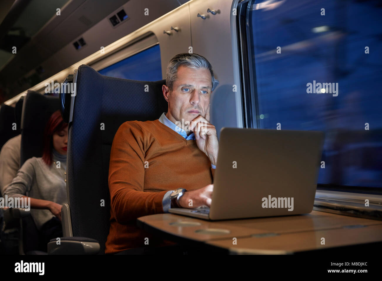 Konzentrierte Geschäftsmann am Laptop arbeiten an Personenzug in der Nacht Stockfoto