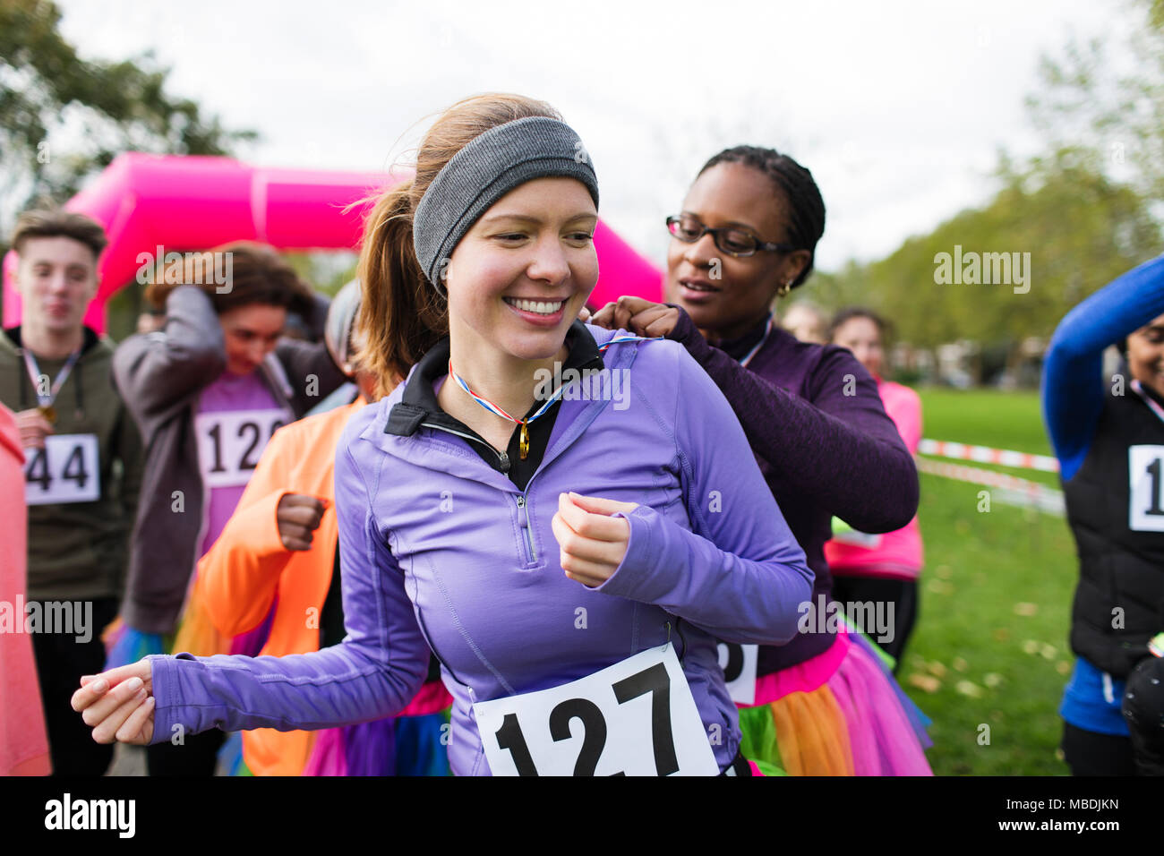 Frau pinning Marathon bib auf Freund an der Nächstenliebe laufen im Park Stockfoto