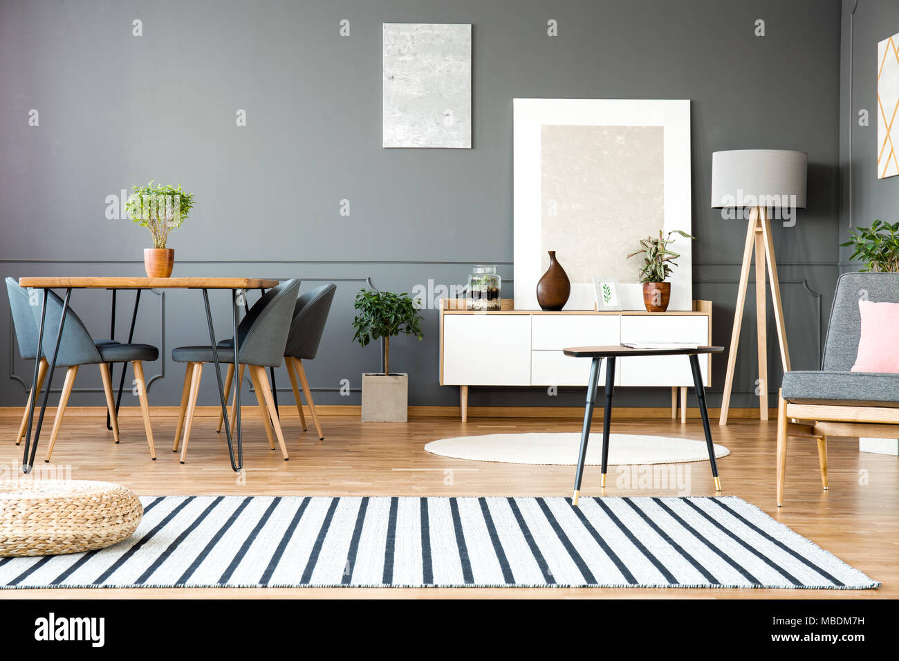 Gestreiften Teppich in Grau open space Interieur mit Stühle am Esstisch und Gemälden an der Wand Stockfoto