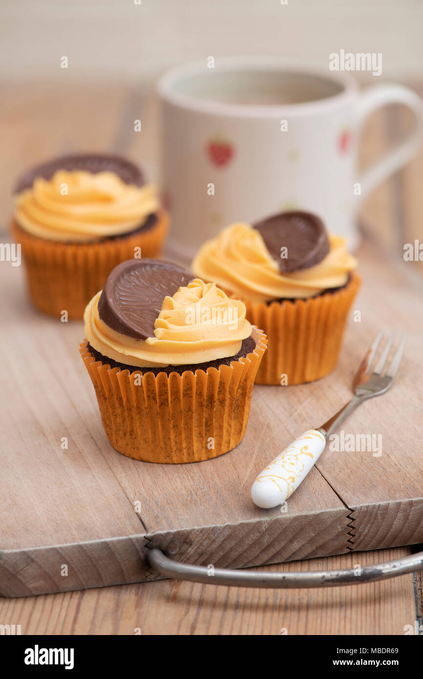 Bunte Schokolade orange Cupcakes auf einem Teller mit einer Tasse Kaffee Stockfoto