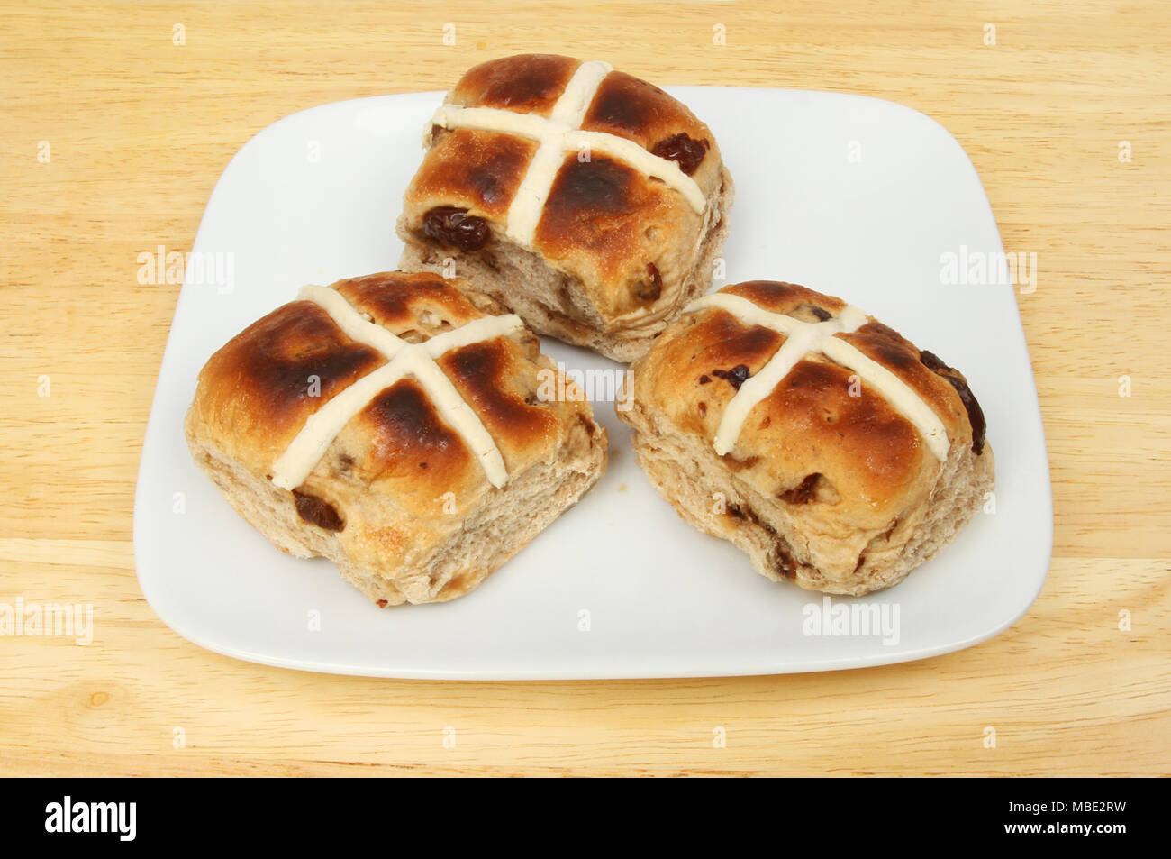 Getoastet Hot Cross Buns auf einer Platte auf einer hölzernen Tischplatte Stockfoto