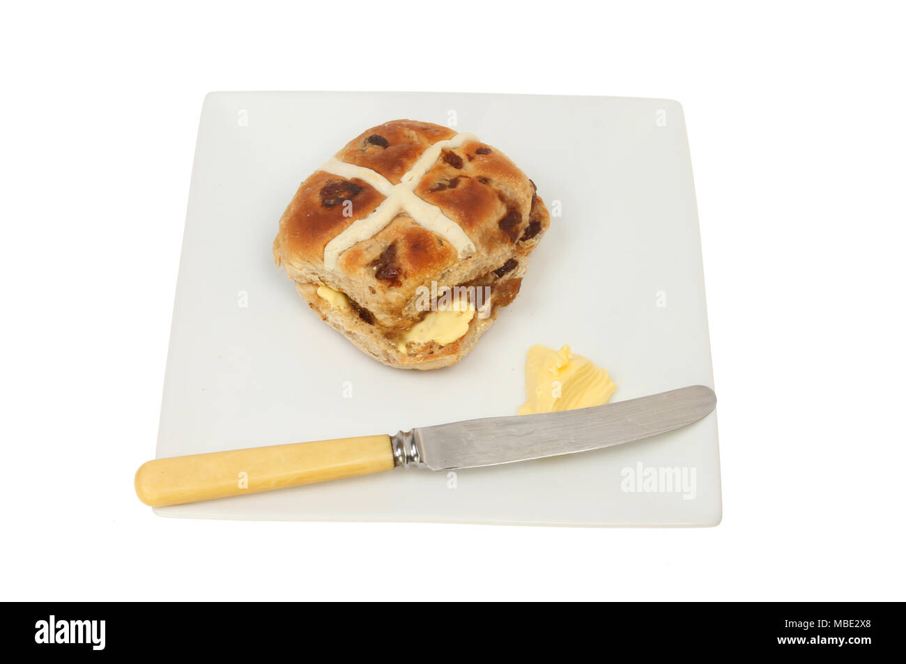 Hot Cross bun auf einem Teller mit Butter und ein Messer gegen Weiße isoliert Stockfoto