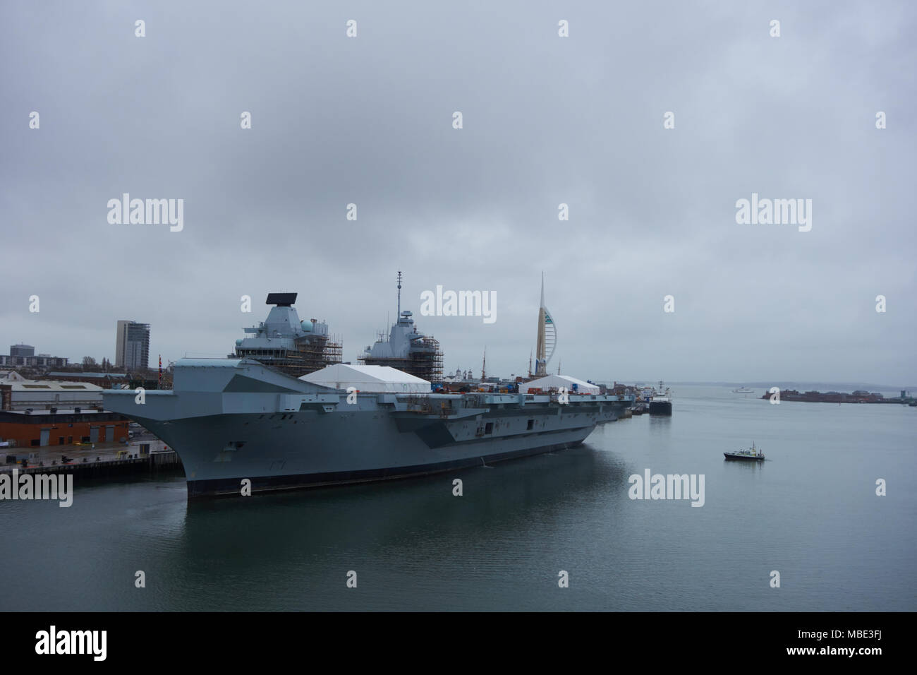 Mit Blick auf den Hafen von Royal Navy HMS Queen Elizabeth unter Wartung, mit Polizei Patrouillenboote auf der Hut in Portsmouth, Großbritannien Stockfoto