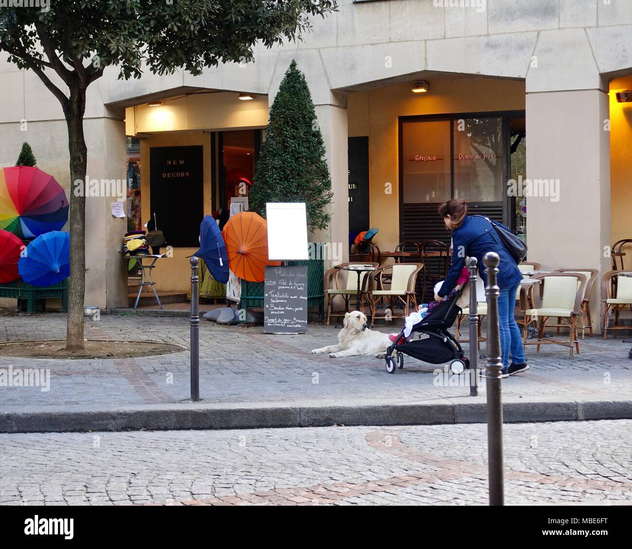 Mutter und Kind im Kinderwagen, stoppen Sie einen süßen Hund vor einem Cafe zu bewundern, die noch nicht für den Tag für Sie geöffnet. Paris, Frankreich. Stockfoto
