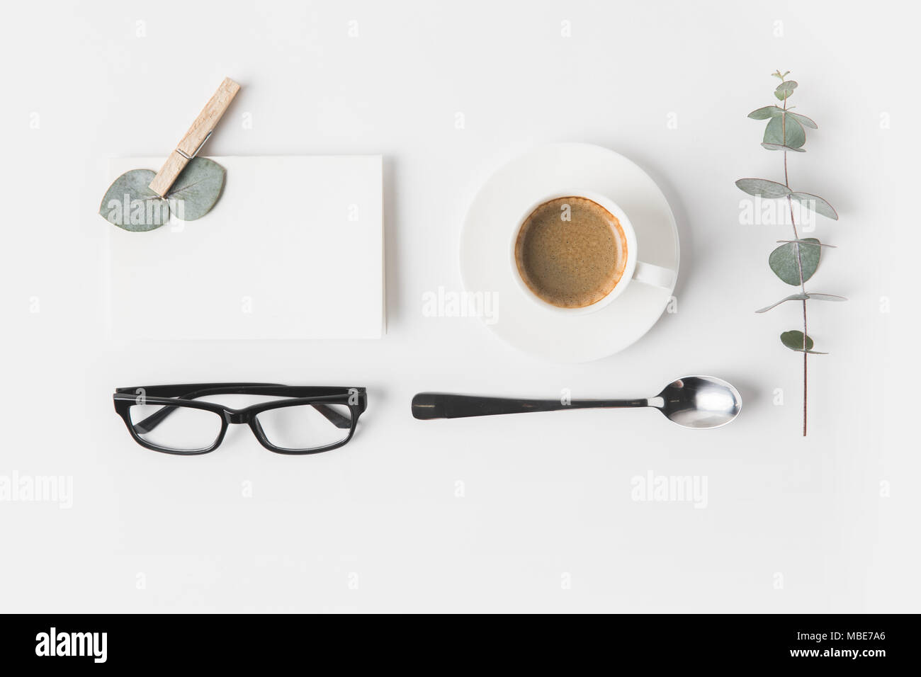 Blick von oben auf die Brillen, Tasse Kaffee, Serviette und Anlage auf weiße Oberfläche Stockfoto