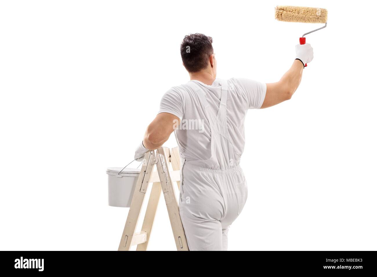 Ansicht von hinten erschossen von einem Maler kletterte auf eine Leiter Malerei mit einer Rolle auf weißem Hintergrund Stockfoto