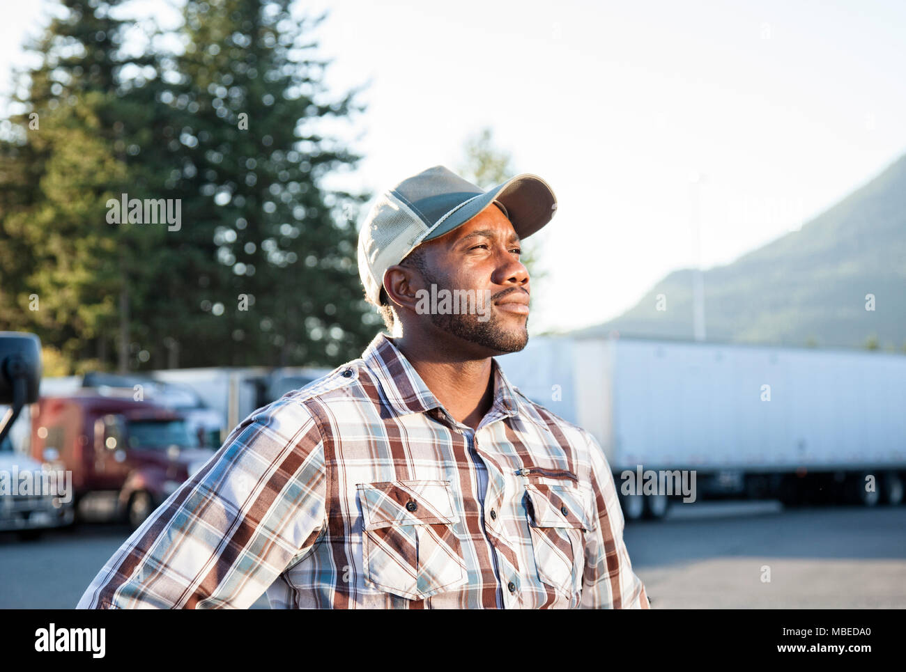 Schwarzer Mann, der LKW-Fahrer in der Nähe von seinen Lkw auf einem Parkplatz an einem Truck Stop geparkt Stockfoto