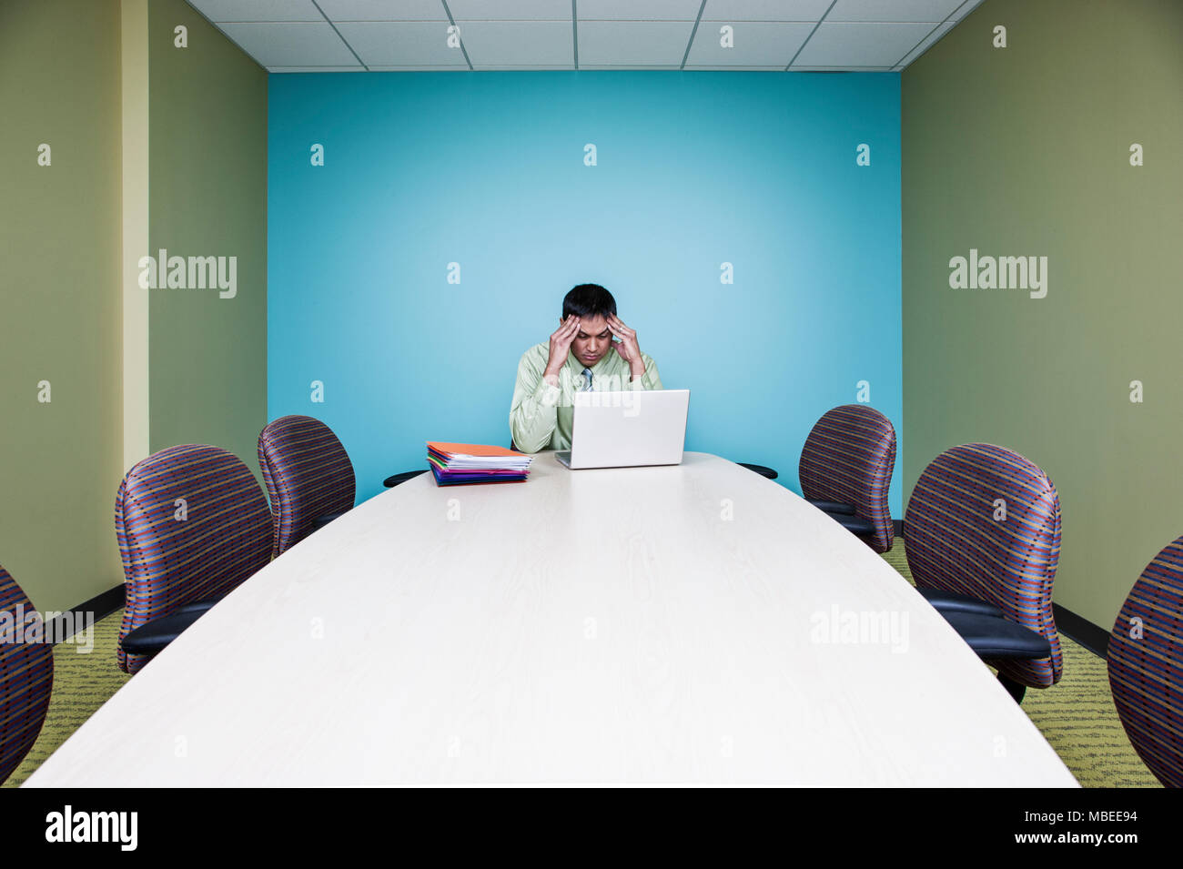 Geschäftsmann in einer stressigen Situation an einem Tisch sitzen in einem Konferenzraum. Stockfoto