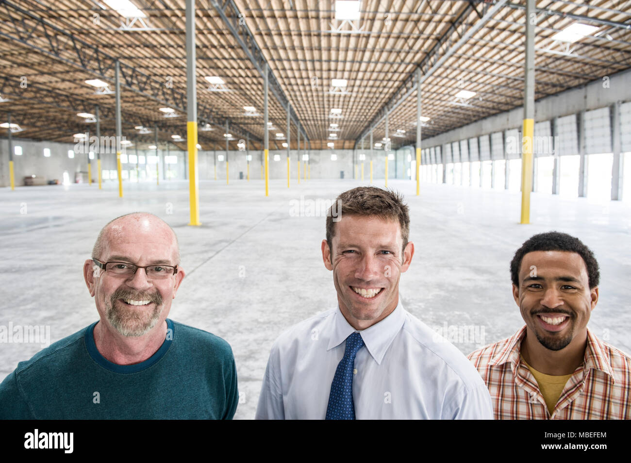 Multi-ethnischen Gruppe von Menschen stand vor der Laderampe Türen in eine neue leere Lager. Stockfoto