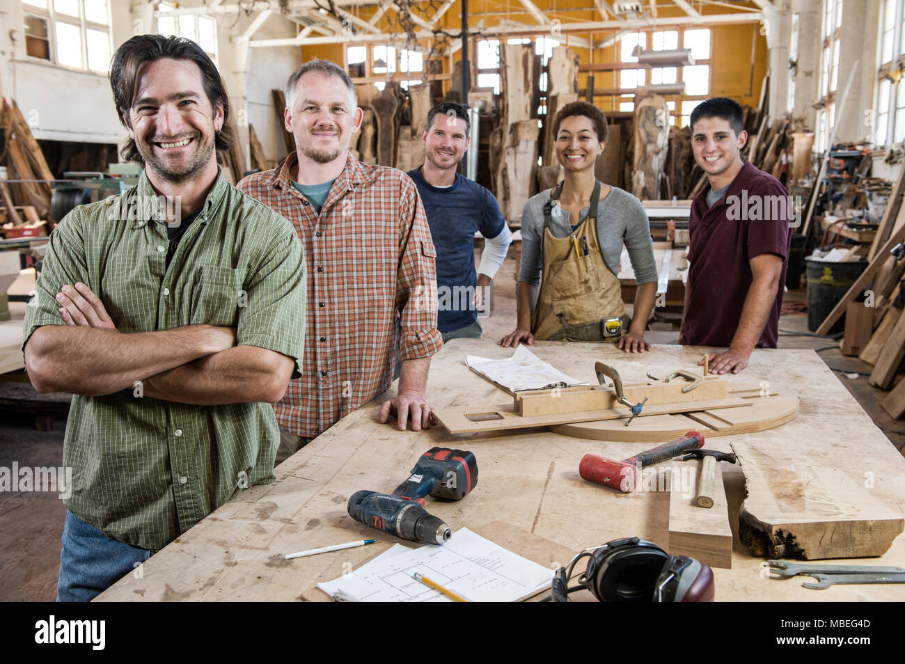 Team von multi-ethnischen Arbeiter neben einem Arbeitsplatz in einem großen Wald, die Fabrik steht. Stockfoto