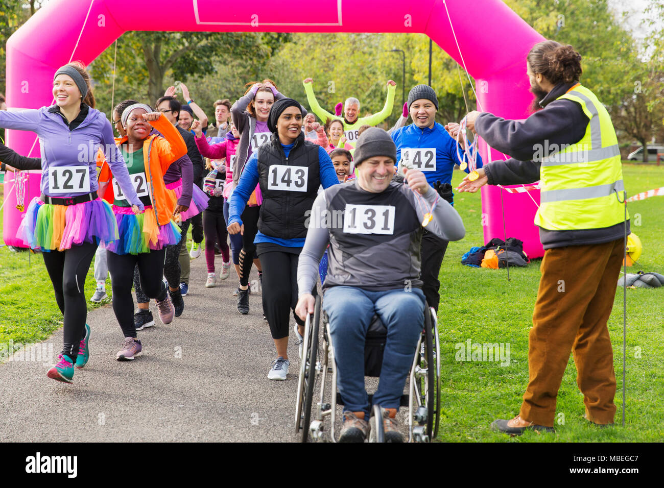 Mann im Rollstuhl und Läufern Medaillen erhalten, Kreuzung Charity race Finish Line Stockfoto