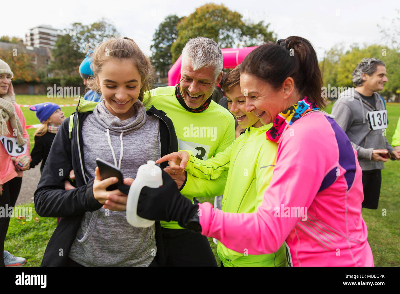 Familie Läufer mit Smart Phone an der Nächstenliebe laufen im Park Stockfoto