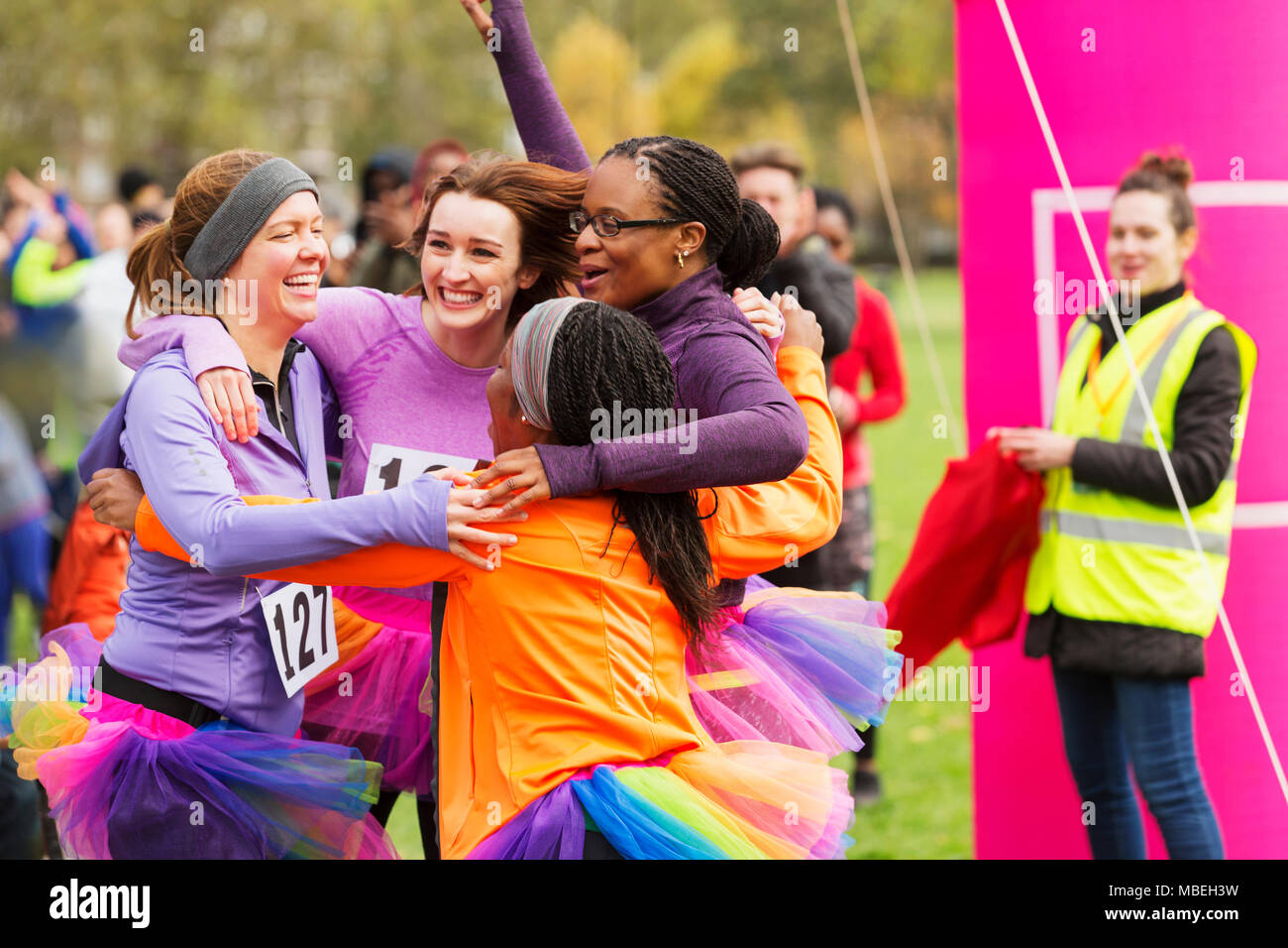 Begeisterte Läuferinnen mit tütü umarmen an der Ziellinie, Feiern Stockfoto