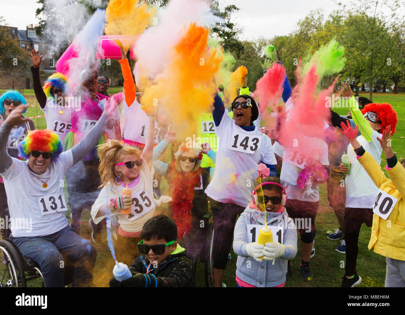 Verspielte Spendenlauf Läufer feiern mit Holi Pulver in Park Stockfoto