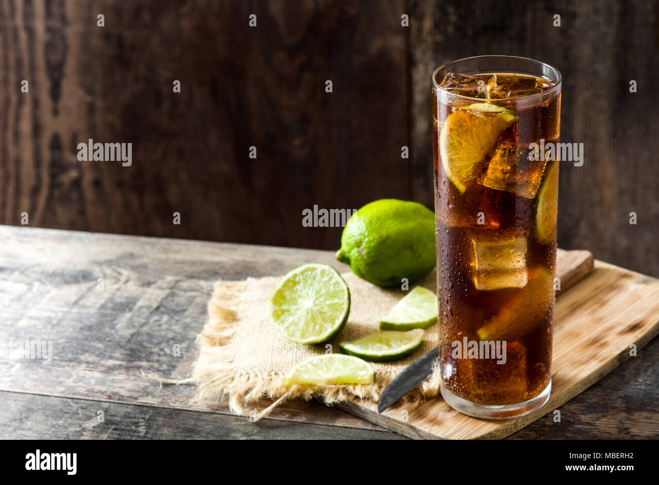 Cuba Libre. Cocktail mit Rum, Limetten und Eis auf Holztisch. Stockfoto