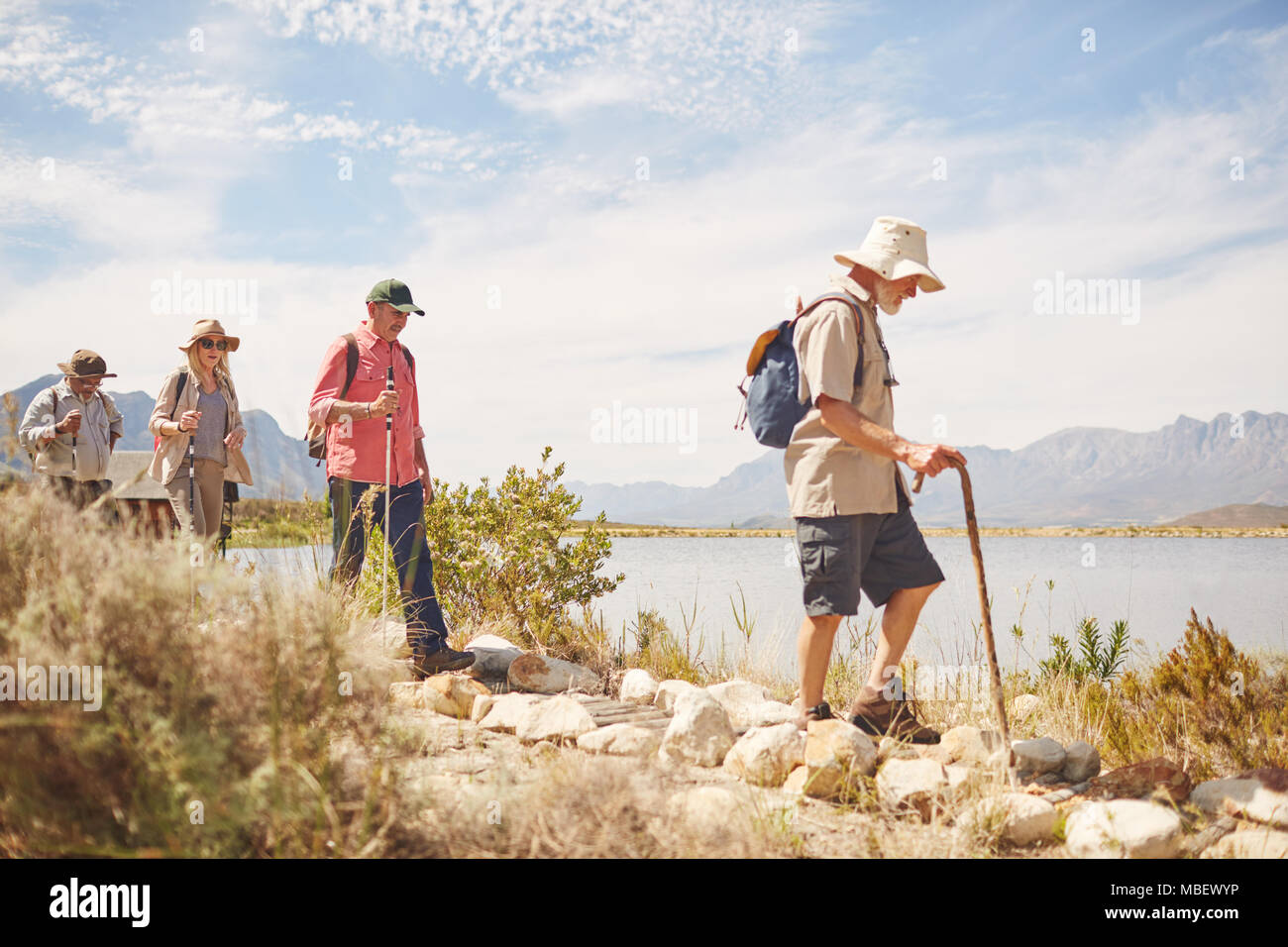 Active Senior Freunden Wandern entlang sonniger Sommer See Stockfoto