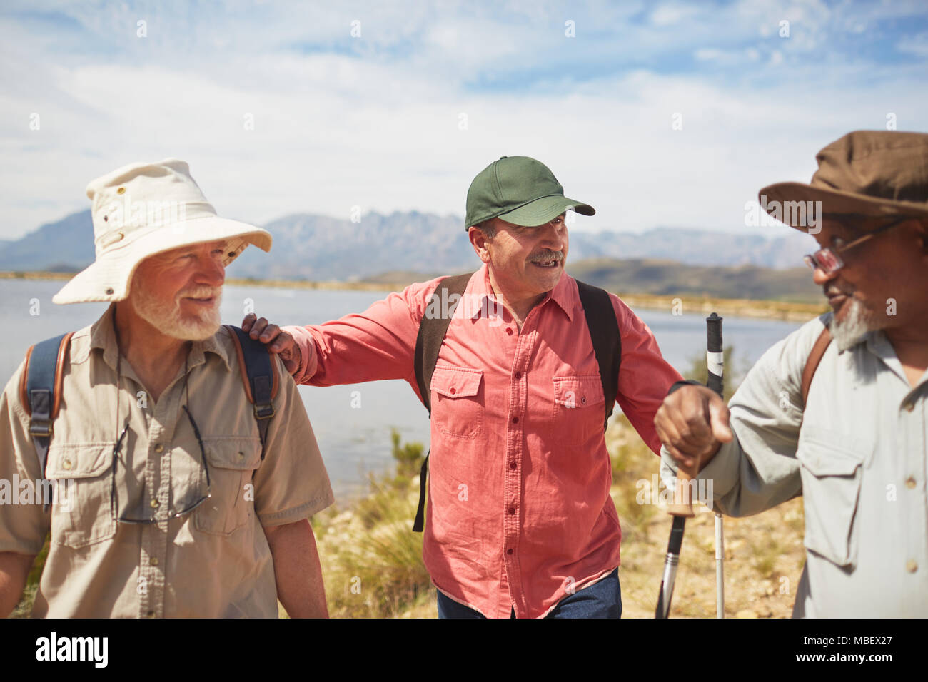 Aktive ältere Männer Freunde Wandern am sonnigen Seeufer Stockfoto