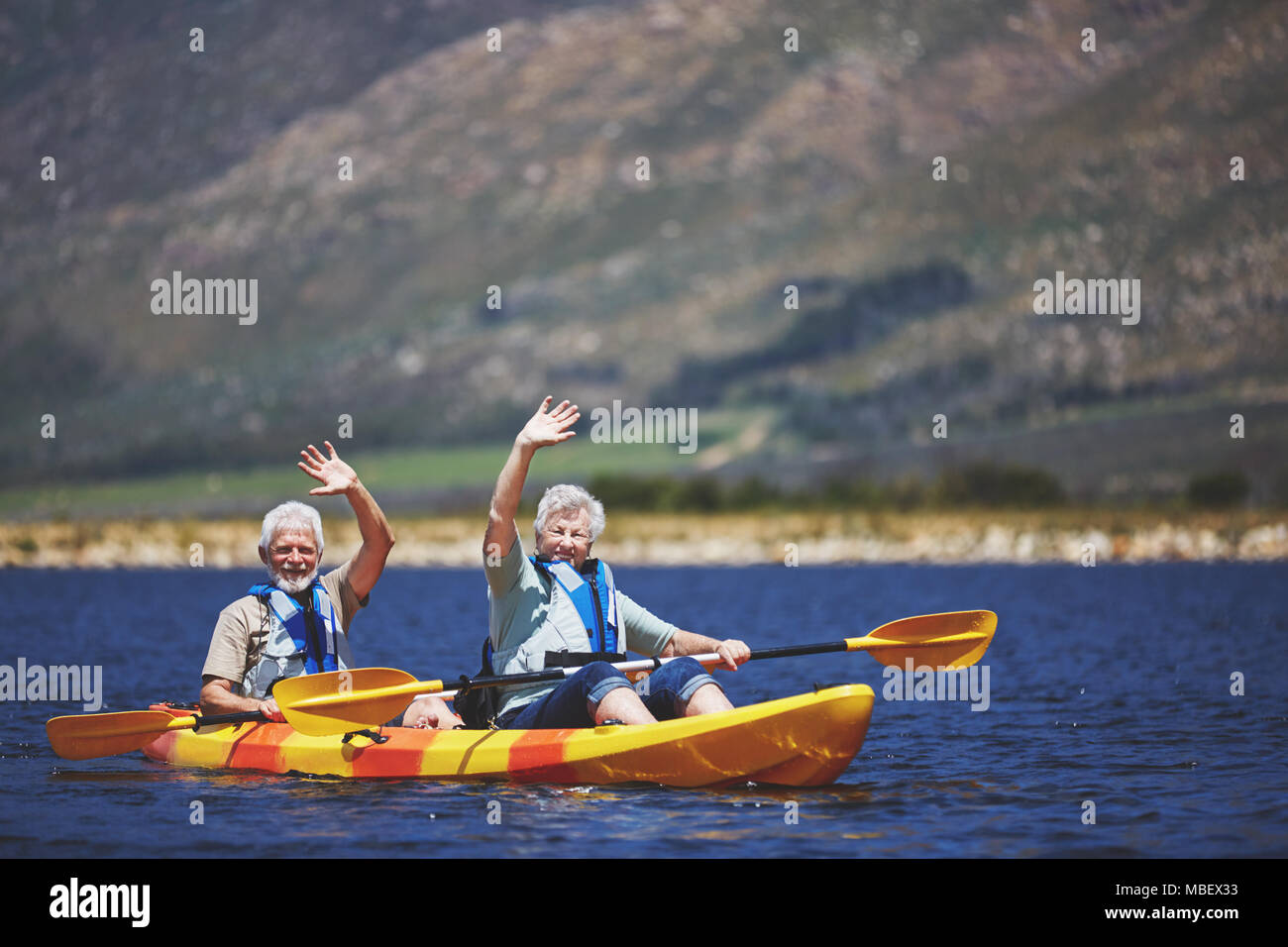 Portrait Active Senior Paar in Kajak winken an sonnigen Sommer See Stockfoto