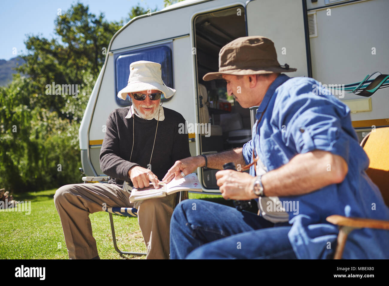 Ältere Männer Freunde auf der Suche nach Ratgeber außerhalb Wohnmobil im sonnigen Sommer Campingplatz Stockfoto