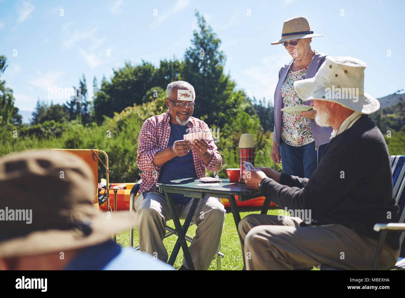 Verspielte Active Senior Freunden Karten spielt im sonnigen Sommer Campingplatz Stockfoto