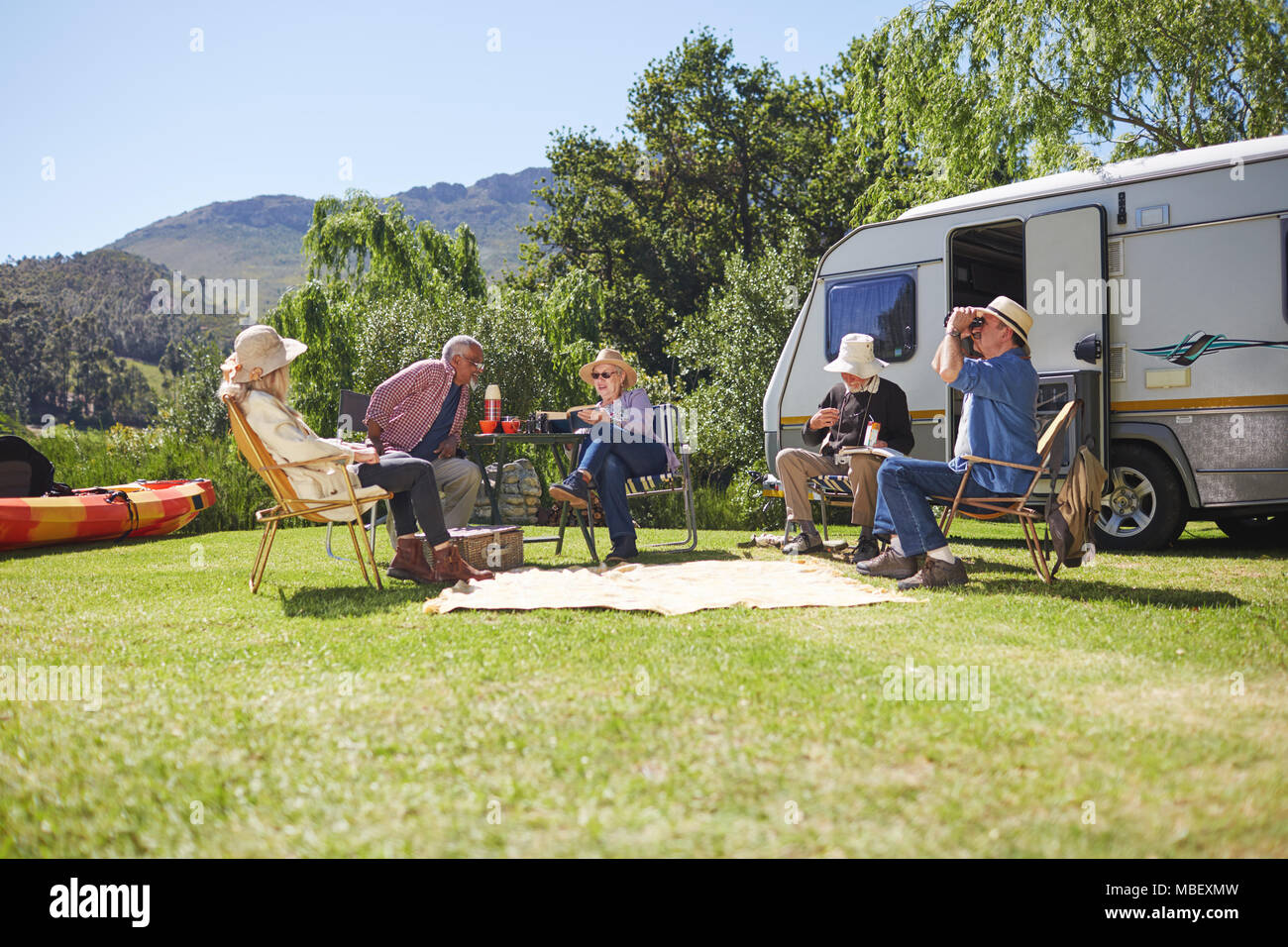 Active Senior Freunden entspannende außerhalb Wohnmobil im sonnigen Sommer Campingplatz Stockfoto