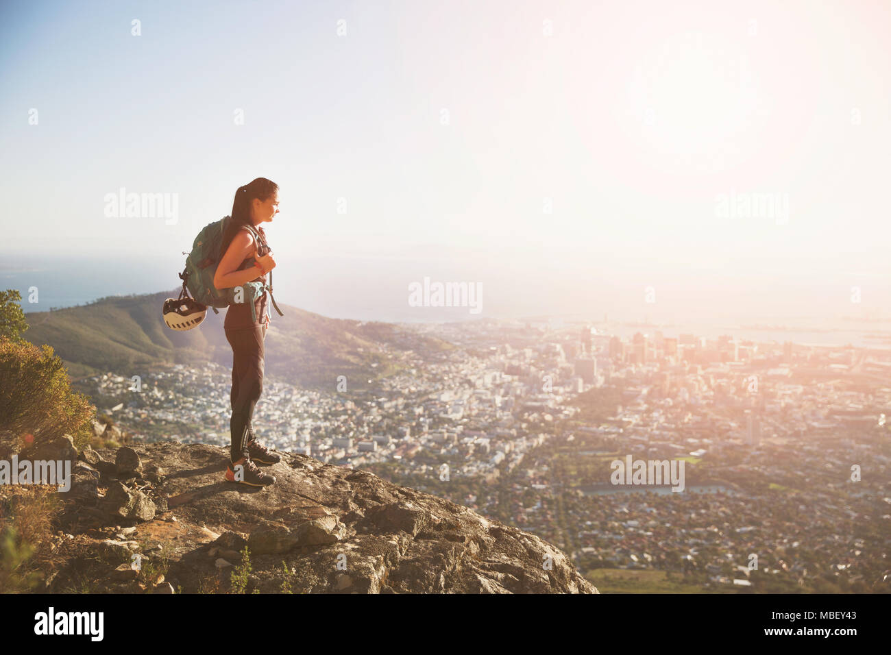 Weibliche Kletterer auf dem Hügel mit Blick auf die sonnige Stadt Stockfoto