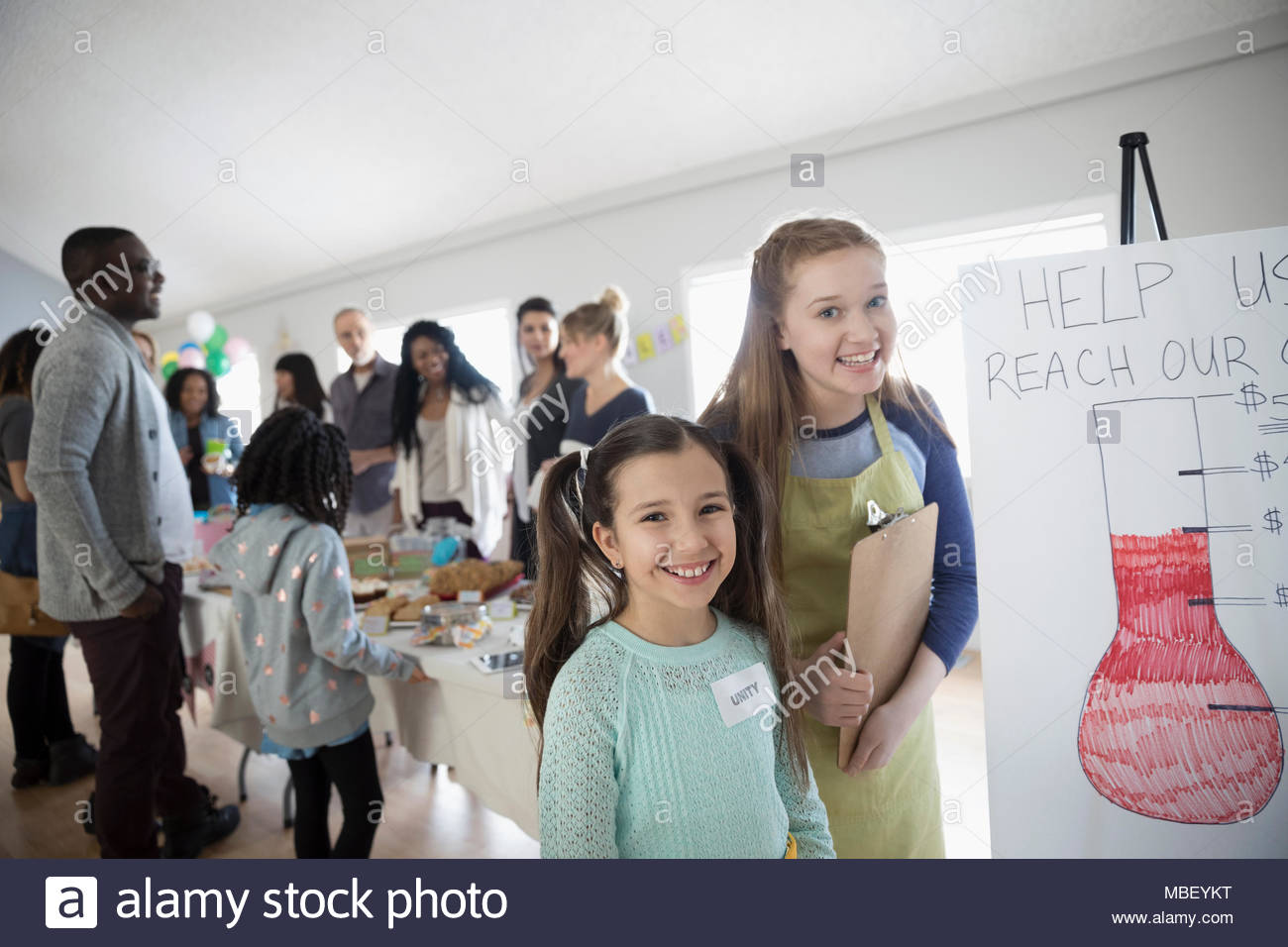 Porträt Lächeln, selbstbewusste Mädchen stehend an fundraising Plakat an backen Verkauf im Community Center Stockfoto