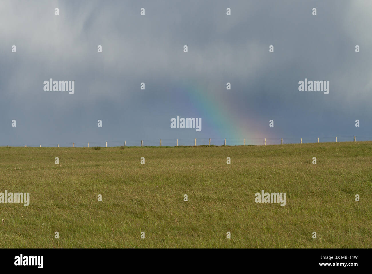 Ein Regenbogen und bewölktem Himmel über einem Feld Stockfoto
