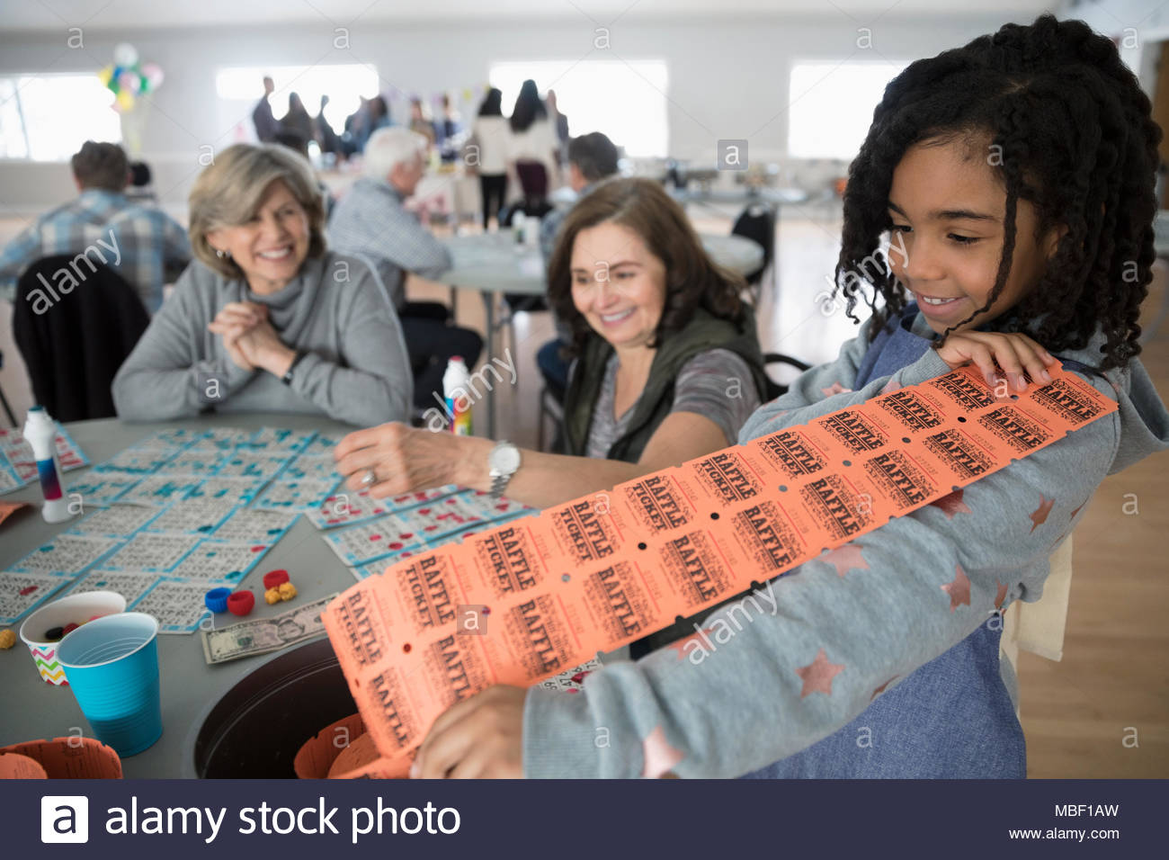 Mädchen verkauf Geldbeschaffung raffle Tickets für Frauen Bingo spielen im Community Center Stockfoto